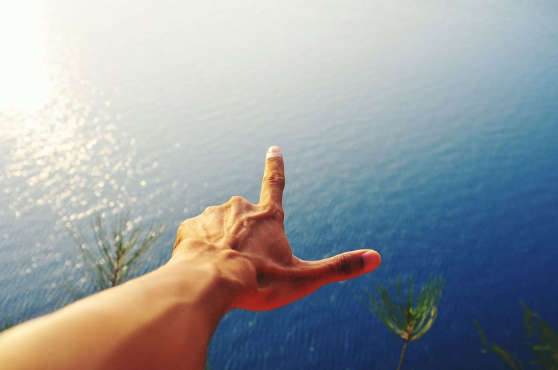 Close-up of person gesturing against lake