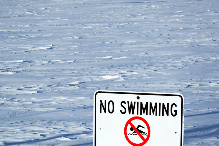 No swimming sign by frozen lake michigan