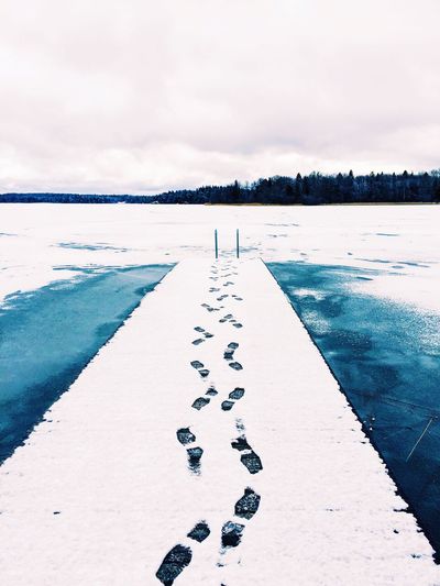 Footprints on pier over frozen river during winter