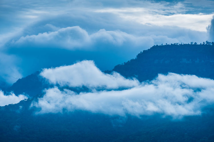 Low angle view of mountains seen through cloud against sky