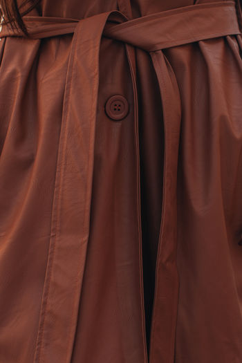 Street style fashion details of autumn trench leather long stylish brown coat. female outfit