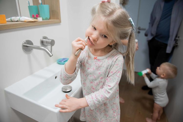Girl brushing teeth by baby boy in bathroom at home