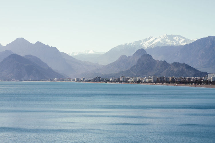 Scenic view of sea and mountains against clear sky