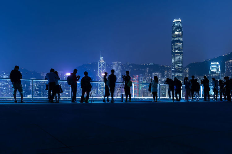 Silhouette shot of hong kong seaside viewpoint with tourists taking photos at night time