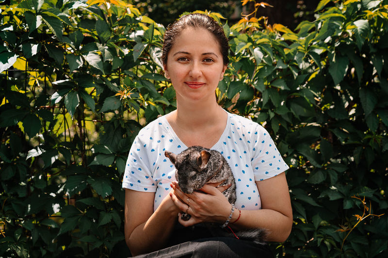 Portrait of smiling young woman holding chinchilla pet
