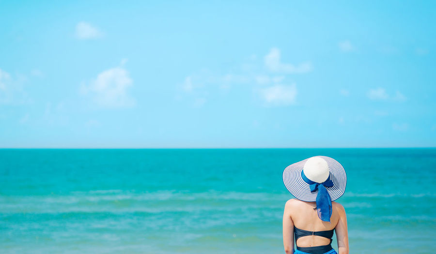 Man wearing hat on beach against sky