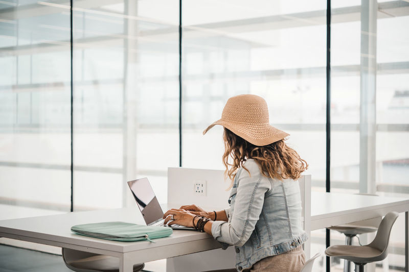 Side view of woman using mobile phone while sitting in cafe