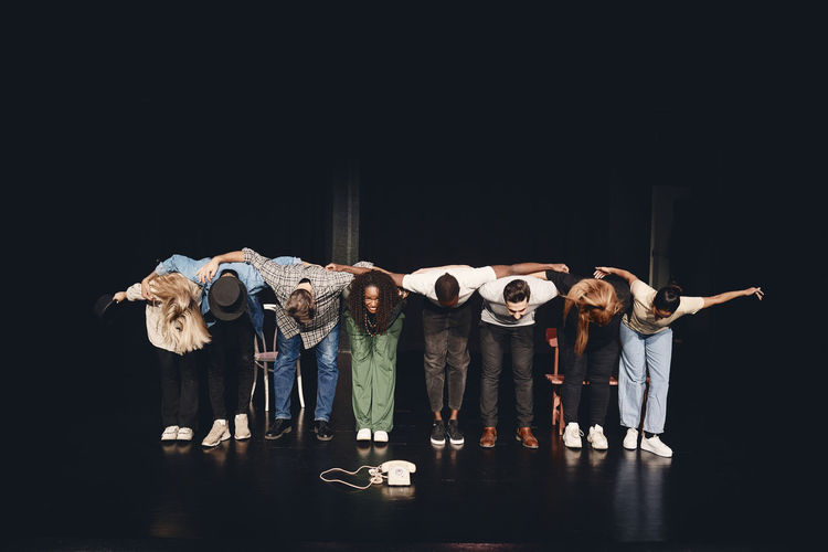 Full length of multiracial male and female artists bowing together on stage