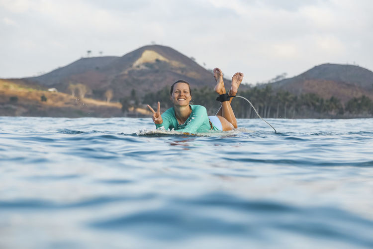 Portrait of smiling woman in water against mountain