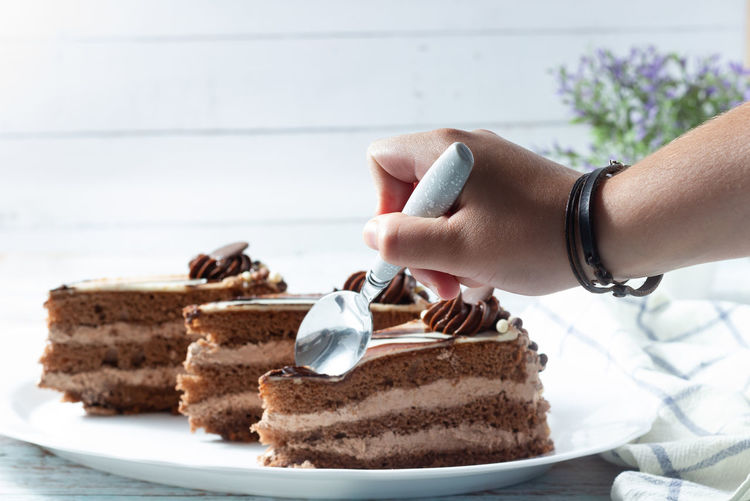  hand holding a slice of delicious chocolate cake with fluffy cocoa sponge  and marble effect icing.