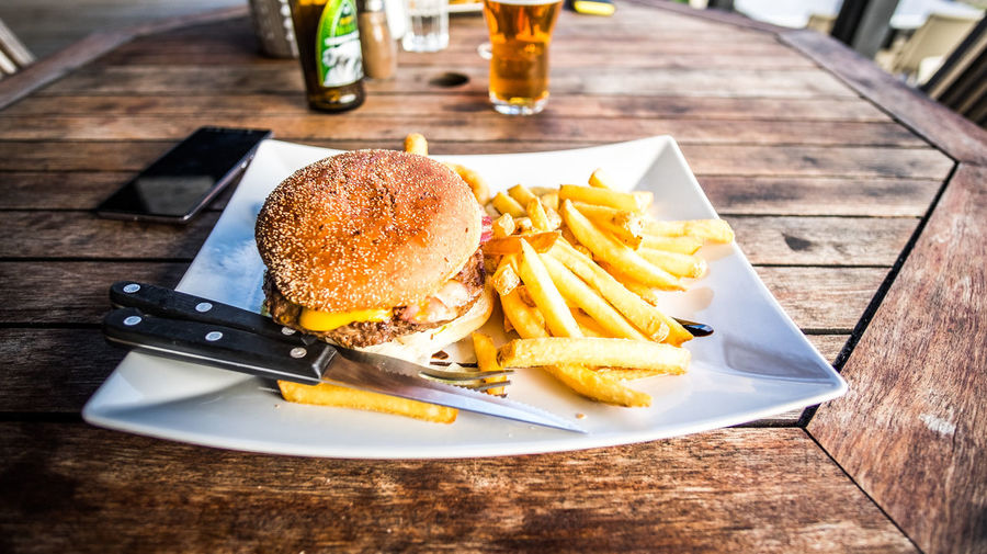 High angle view of hamburger and french fries served in plate on wooden table