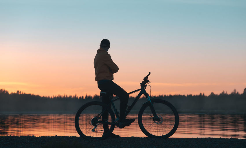 Cyclist enjoys the sunset near the forest lake