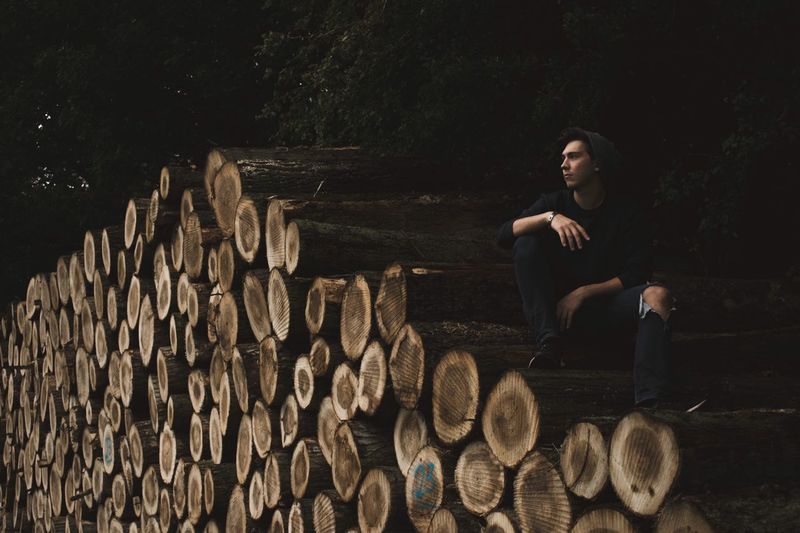 Full length of young woman sitting on logs