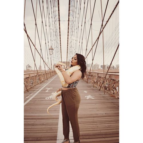 Young woman holding snake on brooklyn bridge