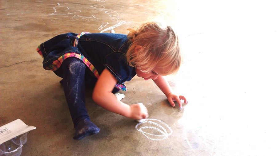 Girl drawing with chalk on floor