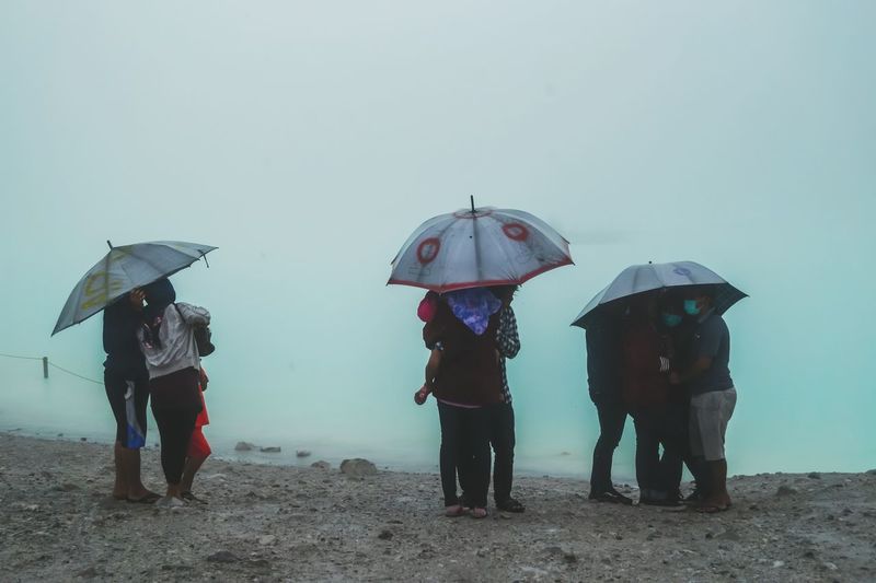 Rear view of people standing under umbrellas
