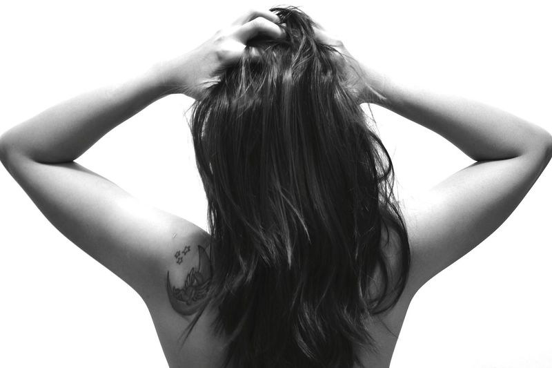 Rear view of woman with hand in hair against white background