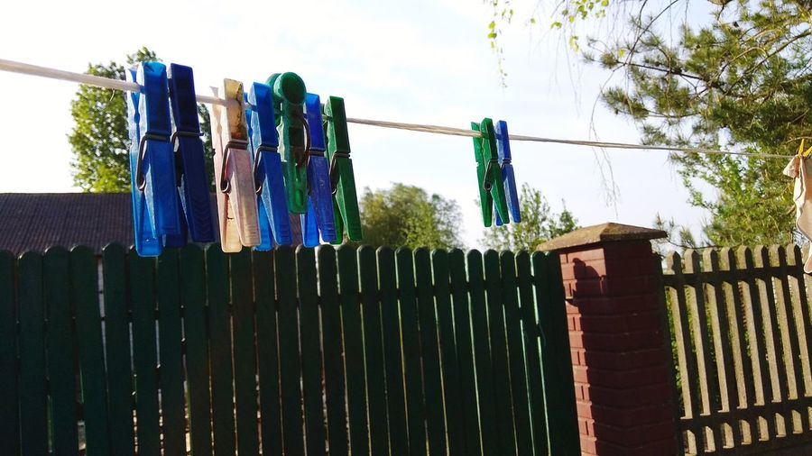 Low angle view of clothesline hanging on fence against sky
