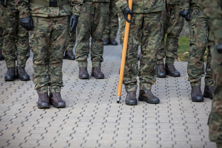 Polish soldiers stand at attention and one of them holds a flag pole.
