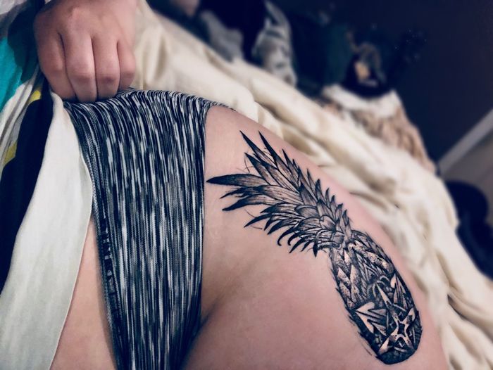 Close-up of tattoo on woman lying on bed 