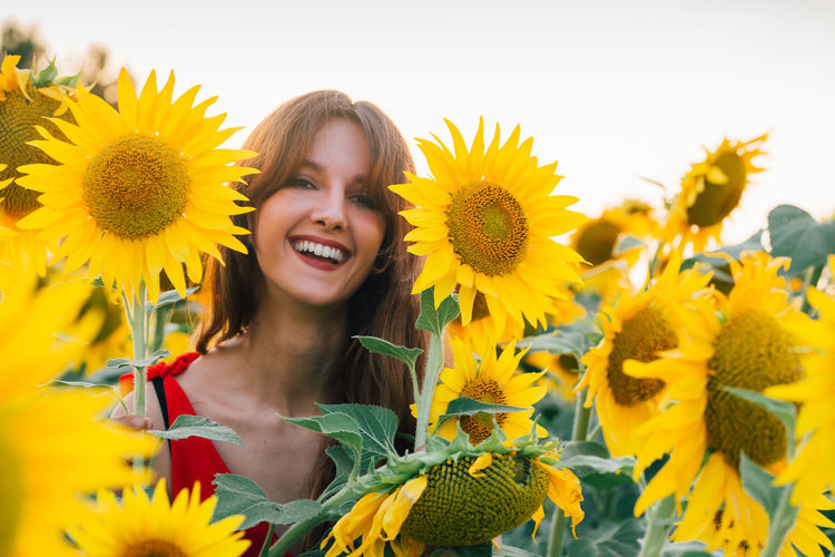 Portrait of smiling woman by sunflower