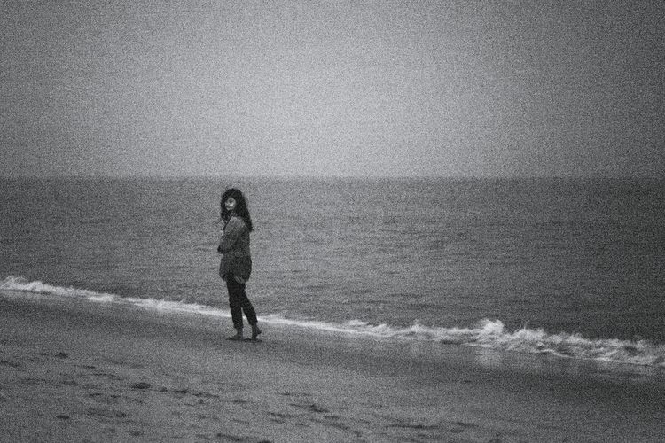 Woman walking at beach against sky