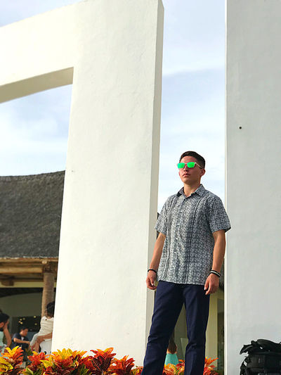 Teenage boy wearing sunglasses standing against wall