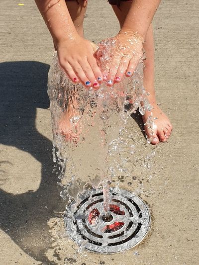 Low section of girl playing with water through fountain