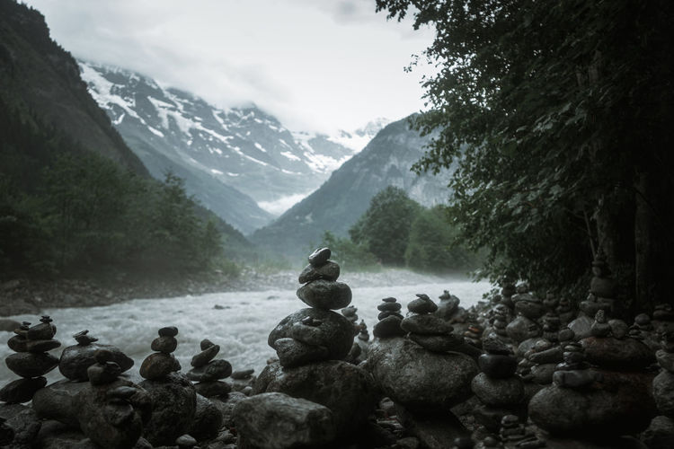 Stack of rocks by river against mountain range