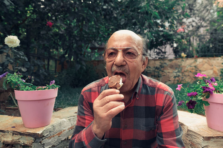 Close-up portrait of senior man eating ice cream. elderly man eating ice cream on stick.