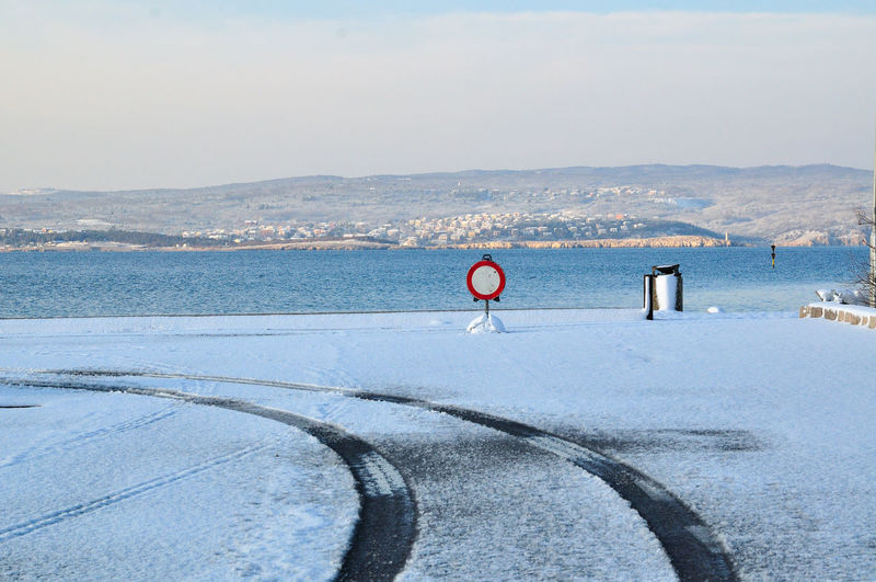 Scenic view of snow covered land and sea against sky