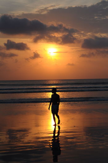 Silhouette man on beach against sky during sunset