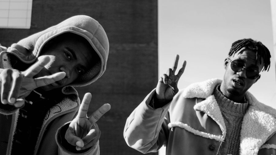Portrait of friends showing peace sign while standing outdoors