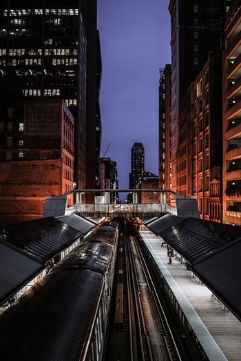 High angle view of train at station amidst buildings in city during night