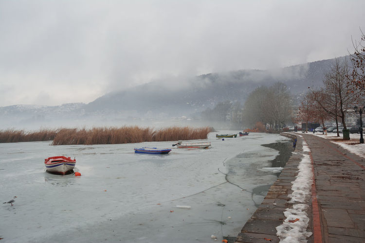 Pedestrian alley on the banks of frozen lake orestiada in kastoria of greece on a cloudy day