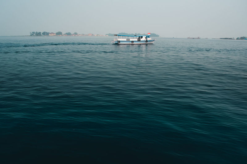 Boat sailing in sea against clear sky