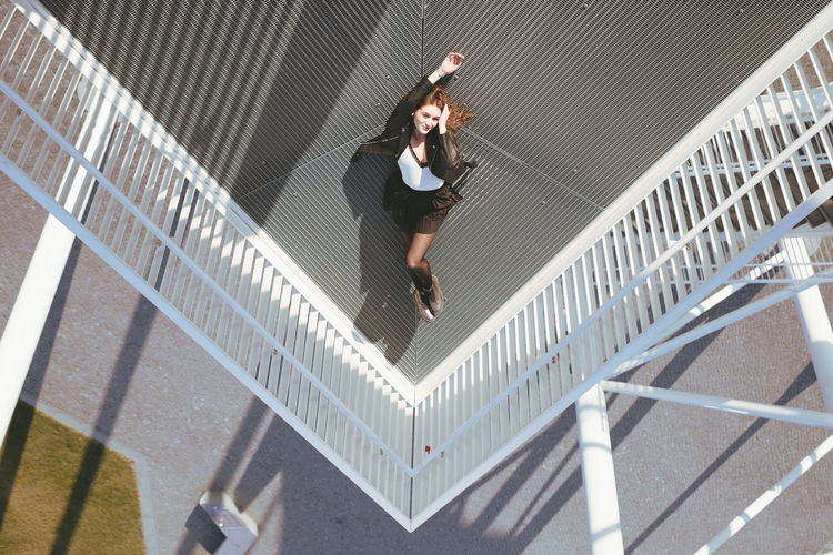 High angle view of young woman lying down on elevated walkway