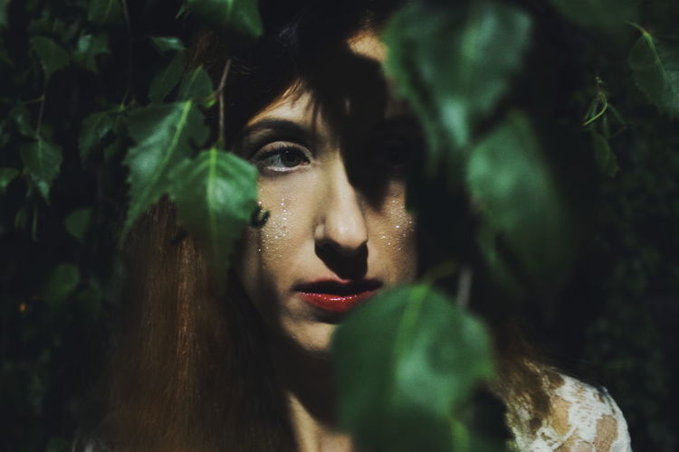 Close-up of young woman seen through leaves