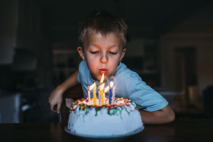 Boy blowing birthday candles in darkroom