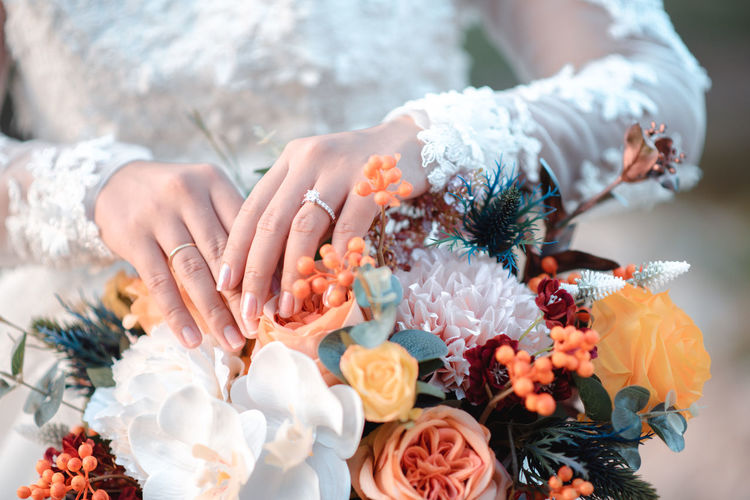 Midsection of woman holding flower bouquet outdoors