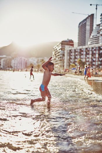 Low angle view of boy playing at sea shore