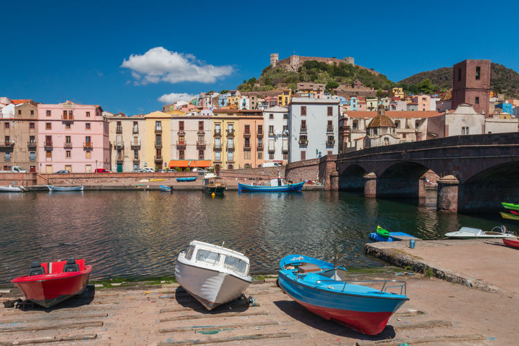 Colorful houses along waterfront in bosa on the italian island of sardinia against sky 