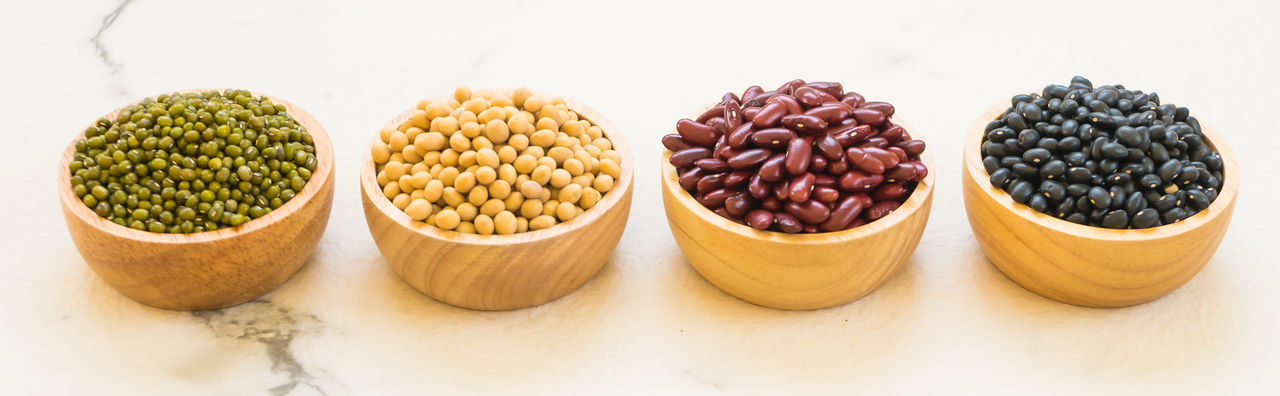 High angle view of various beans in bowls over white background