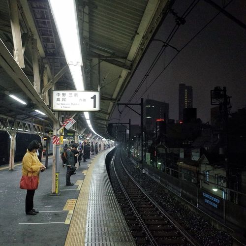Commuters waiting at railroad station platform at night
