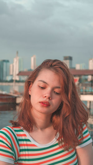 Portrait of woman in city against sky