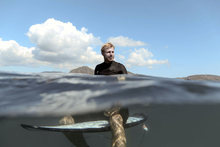 Portrait of happy man posing on surfboard in the sea