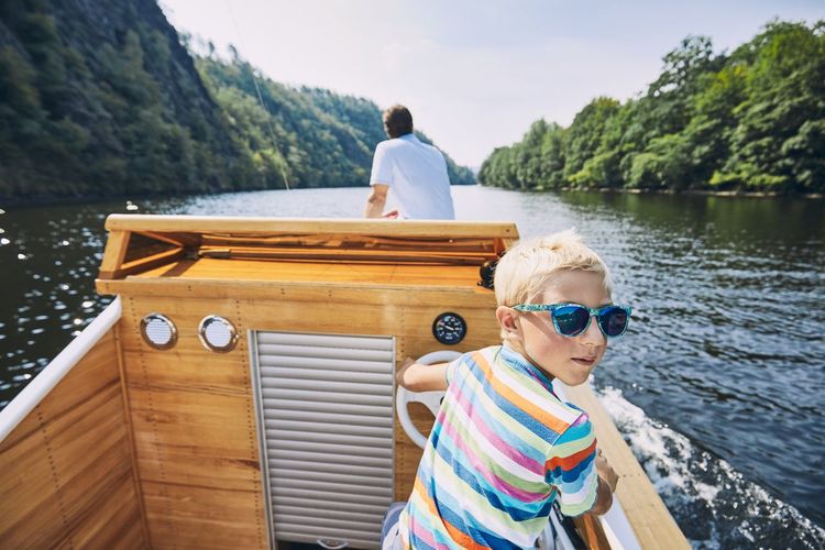 Portrait of boy wearing sunglasses on boat sailing in river