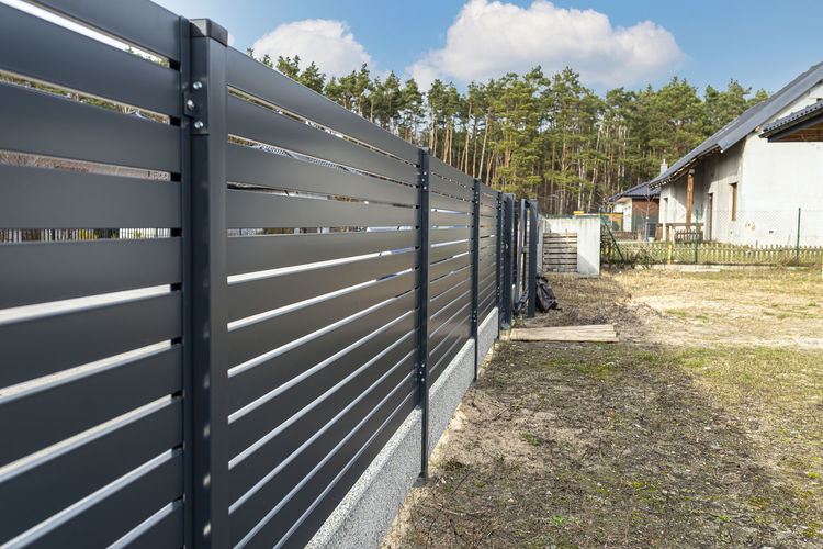 Modern anthracite panel fencing, visible spans and a fence foundation connector, view from garden.