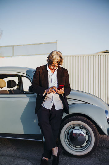 Portrait of young businesswoman using mobile phone while sitting on car