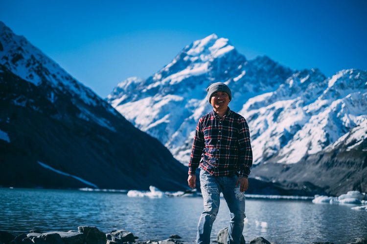 Portrait of man standing on snowcapped mountain against sky